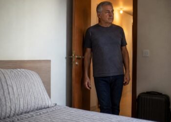Aposentado observa o quarto extra preparado para hóspedes no apartamento