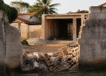 Trecho derrubado do muro da divisa, com blocos quebrados no chão
