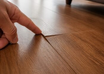Emenda levantada no piso vinílico da sala, sob luz rasante