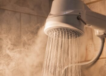 Chuveiro elétrico ligado em banheiro brasileiro, com vapor no ambiente