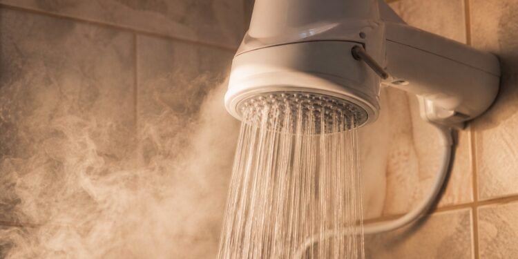 Chuveiro elétrico ligado em banheiro brasileiro, com vapor no ambiente