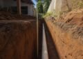 Vala aberta no quintal com o tubo assentado no fundo