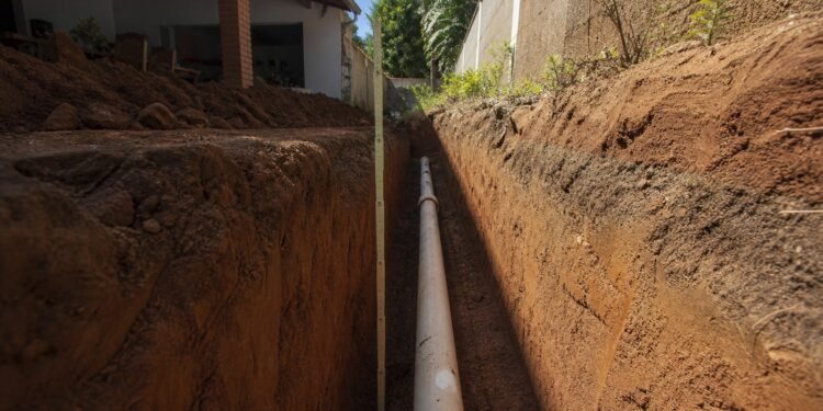 Vala aberta no quintal com o tubo assentado no fundo