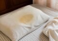 Travesseiro com mancha amarelada no centro sobre a cama sem roupa