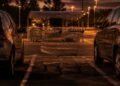 Carrinho abandonado entre carros no estacionamento do mercado ao anoitecer