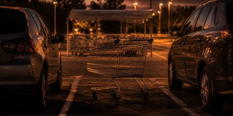 Carrinho abandonado entre carros no estacionamento do mercado ao anoitecer