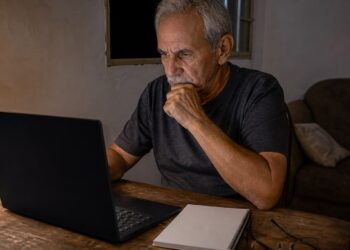 Homem acompanha o leilão pelo computador à noite, em casa