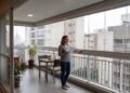 Moradora instala fechamento retrátil na varanda do apartamento para conseguir usar espaço em dias de chuva, investe R$ 28 mil e recebe ordem de retirada depois que condomínio considera estrutura diferente do padrão aprovado