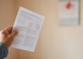 Mão segurando contracheque com calendário de dezembro ao fundo