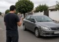Pessoa fotografando o para-choque amassado de um carro na rua
