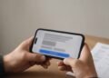 Mãos com celular em tela de autorização de pagamento recorrente