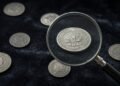 Moedas antigas de aço sobre veludo escuro com lupa
