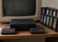 Videogame dos anos oitenta com controles e cartuchos diante de TV de tubo