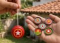 Mão segura ioiô vermelho e outra segura cinco tampinhas estampadas