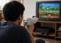 Homem mira pistola de videogame na televisão de tubo